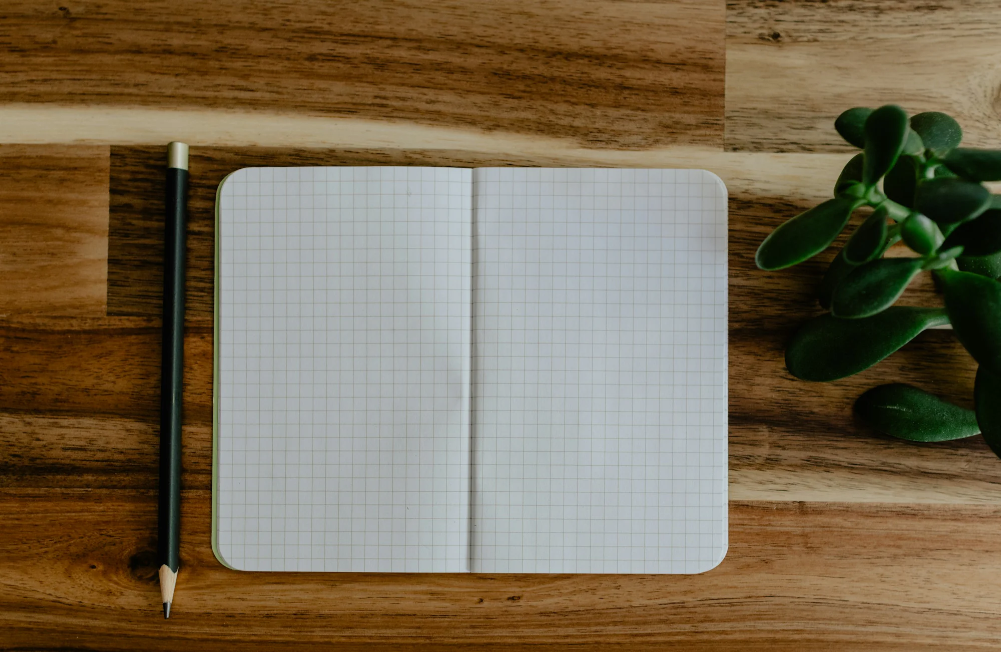 Carnet ouvert et crayon posés sur un bureau en bois
